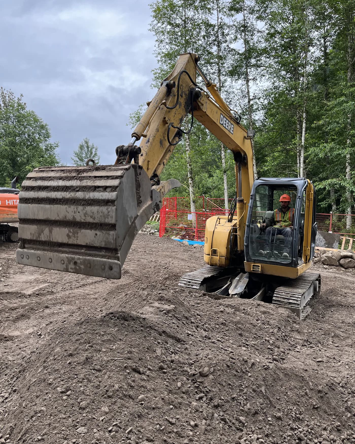 A tracked excavator on open ground at a civil worksite, its bucket lowered