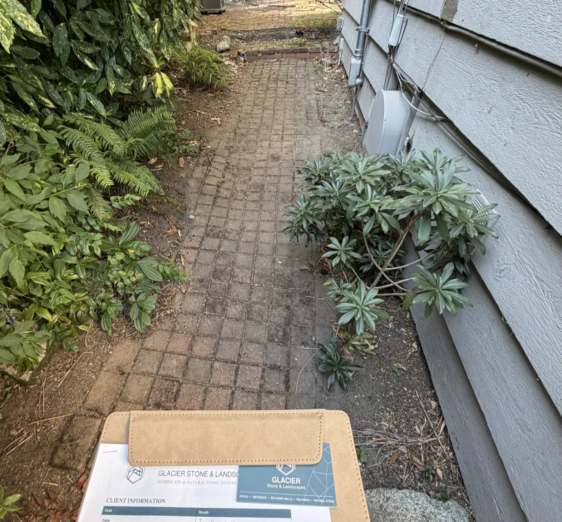 Assessment paperwork on site above a paver walkway with failed joints
